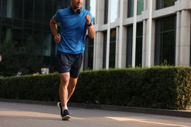 Photo of Man in sportswear running on city street, closeup. Space for text