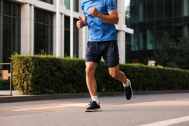 Photo of Man in sportswear running on city street, closeup