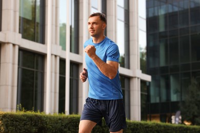 Photo of Man in sportswear running on city street