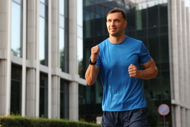 Photo of Man in sportswear running outdoors, low angle view. Space for text