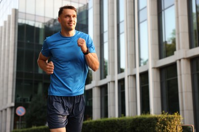 Photo of Man in sportswear running outdoors, low angle view. Space for text