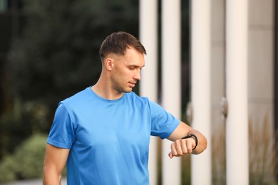 Photo of Man checking fitness tracker before running outdoors