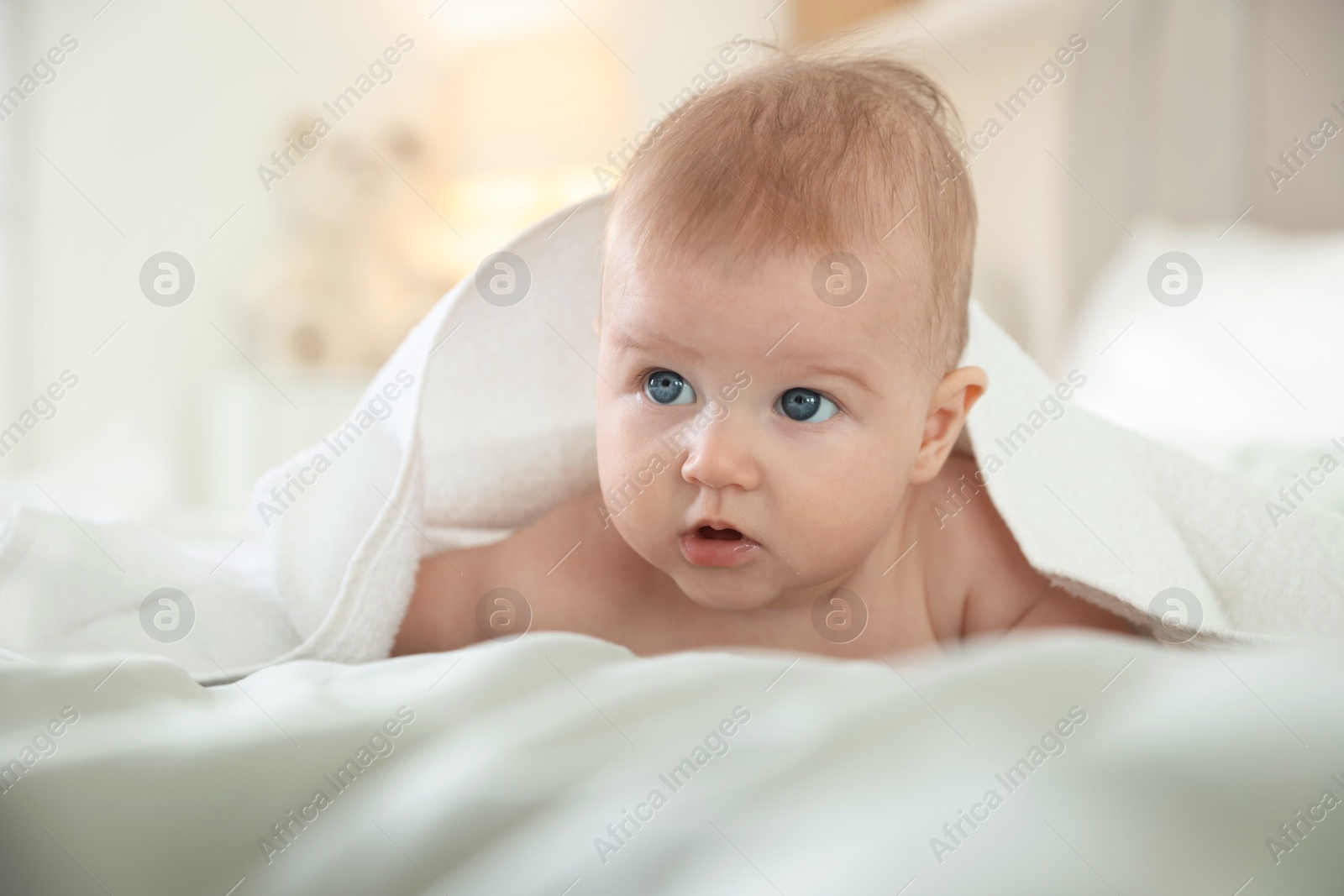 Photo of Cute baby covering with towel after bathing on bed, closeup