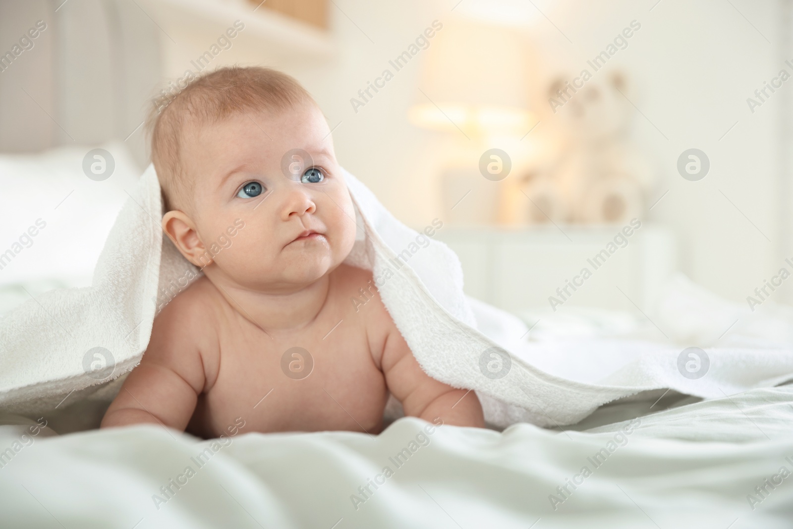 Photo of Cute baby covering with towel after bathing on bed, closeup