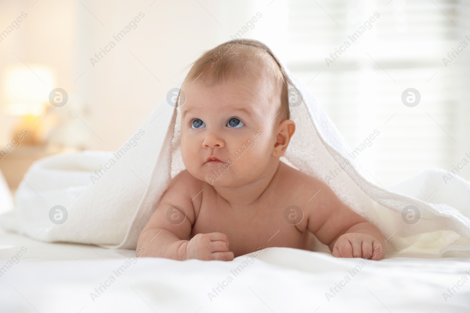 Photo of Cute baby covering with towel after bathing on bed, closeup