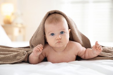Photo of Portrait of cute baby covering with brown towel after bathing on bed, closeup