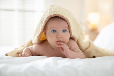 Photo of Cute baby covering with yellow towel after bathing on bed, closeup