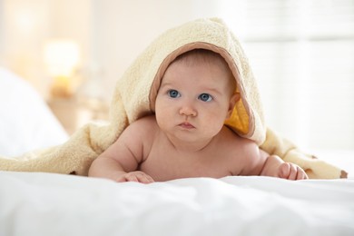 Photo of Cute baby covering with yellow towel after bathing on bed, closeup
