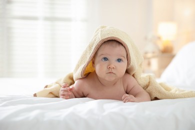 Photo of Cute baby covering with yellow towel after bathing on bed, closeup. Space for text