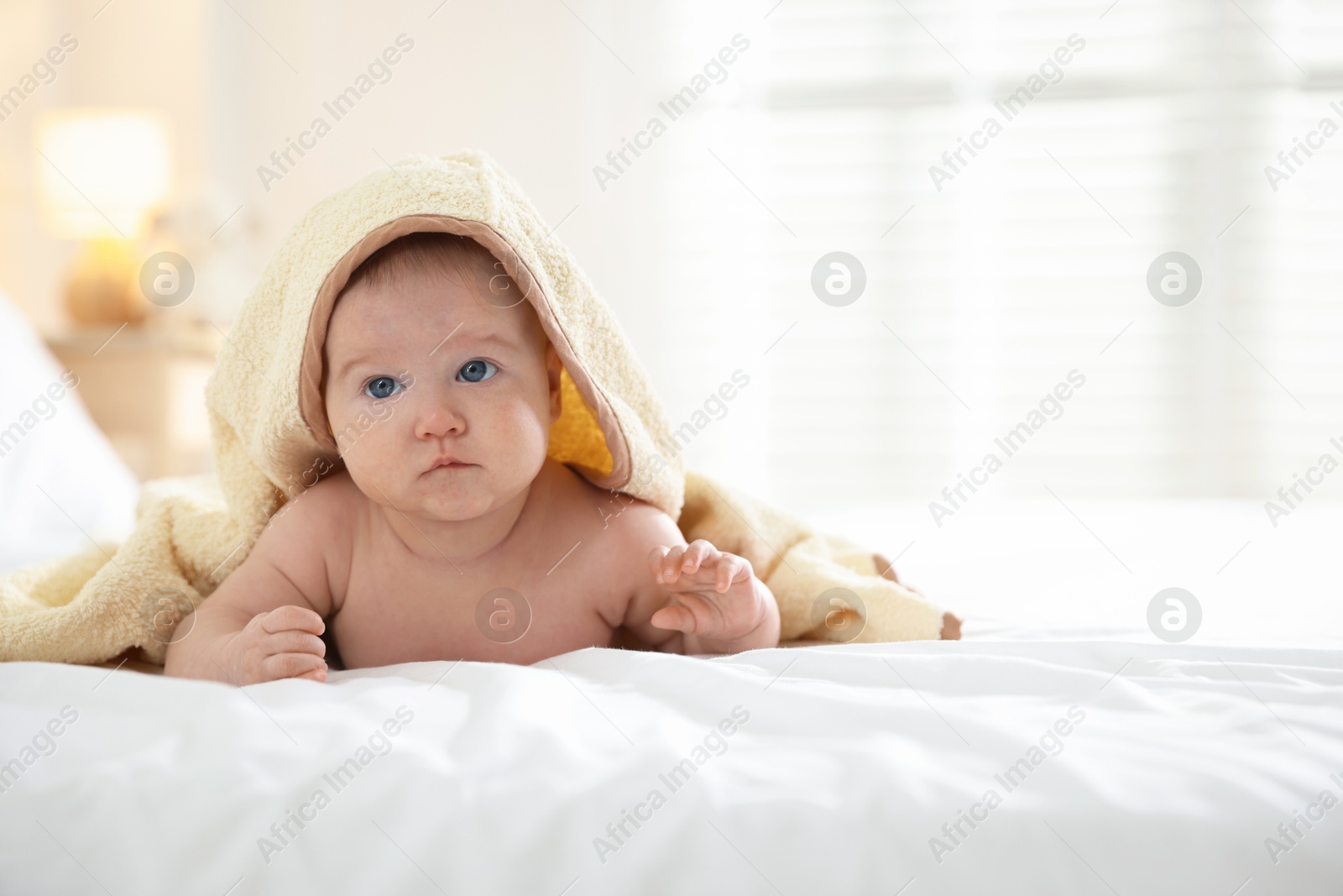 Photo of Cute baby covering with yellow towel after bathing on bed, closeup. Space for text