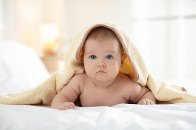 Photo of Cute baby covering with yellow towel after bathing on bed, closeup