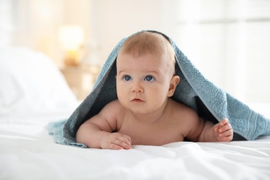 Photo of Cute baby covering with blue towel after bathing on bed, closeup