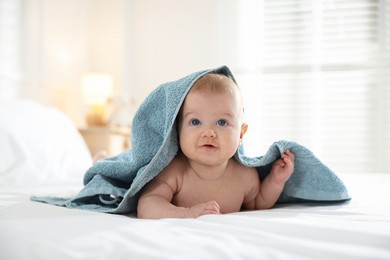 Photo of Cute baby covering with blue towel after bathing on bed, closeup