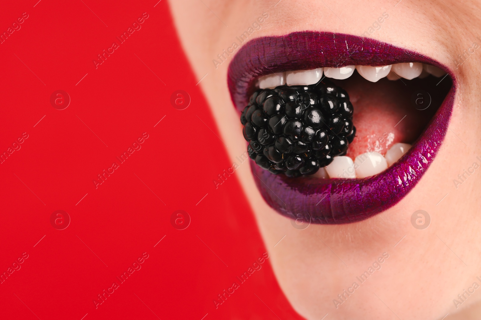 Woman with beautiful lips makeup and blackberry on red background, closeup. Space for text Photo of Woman with beautiful lips makeup and blackberry on red background, closeup. Space for text