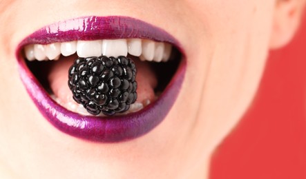 Photo of Woman with beautiful lips makeup and blackberry on red background, closeup