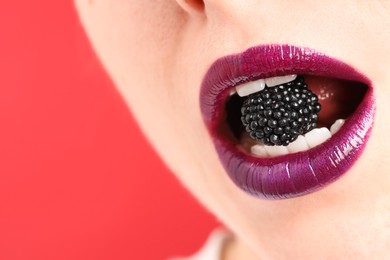 Photo of Woman with beautiful lips makeup and blackberry on red background, closeup. Space for text