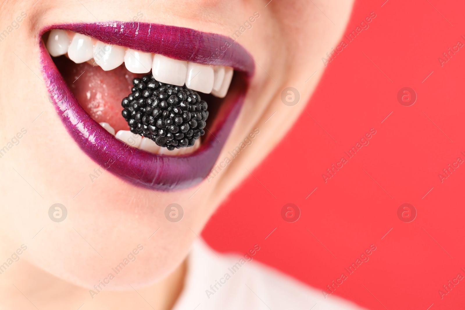 Woman with beautiful lips makeup and blackberry on red background, closeup. Space for text Photo of Woman with beautiful lips makeup and blackberry on red background, closeup. Space for text