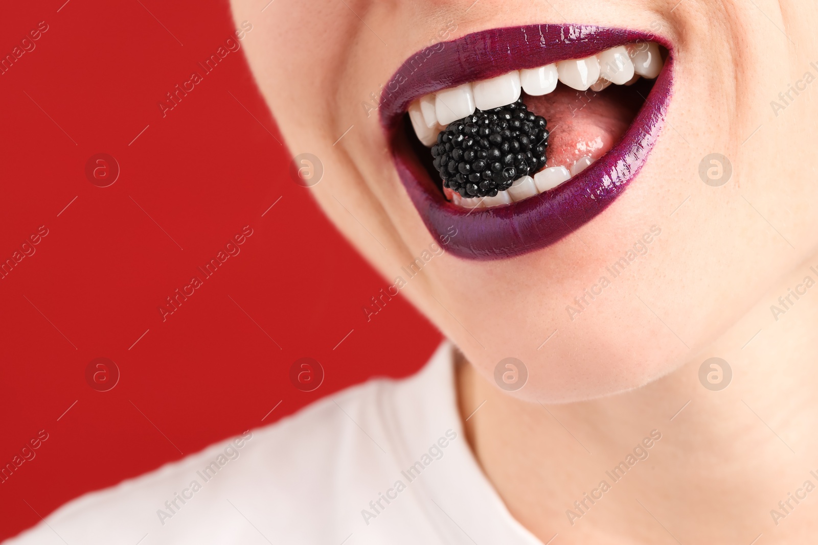 Woman with beautiful lips makeup and blackberry on red background, closeup. Space for text Photo of Woman with beautiful lips makeup and blackberry on red background, closeup. Space for text