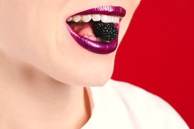 Photo of Woman with beautiful lips makeup and blackberry on red background, closeup. Space for text
