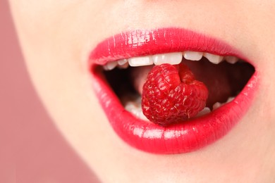 Photo of Woman with beautiful lips makeup and raspberry on dusty pink background, closeup