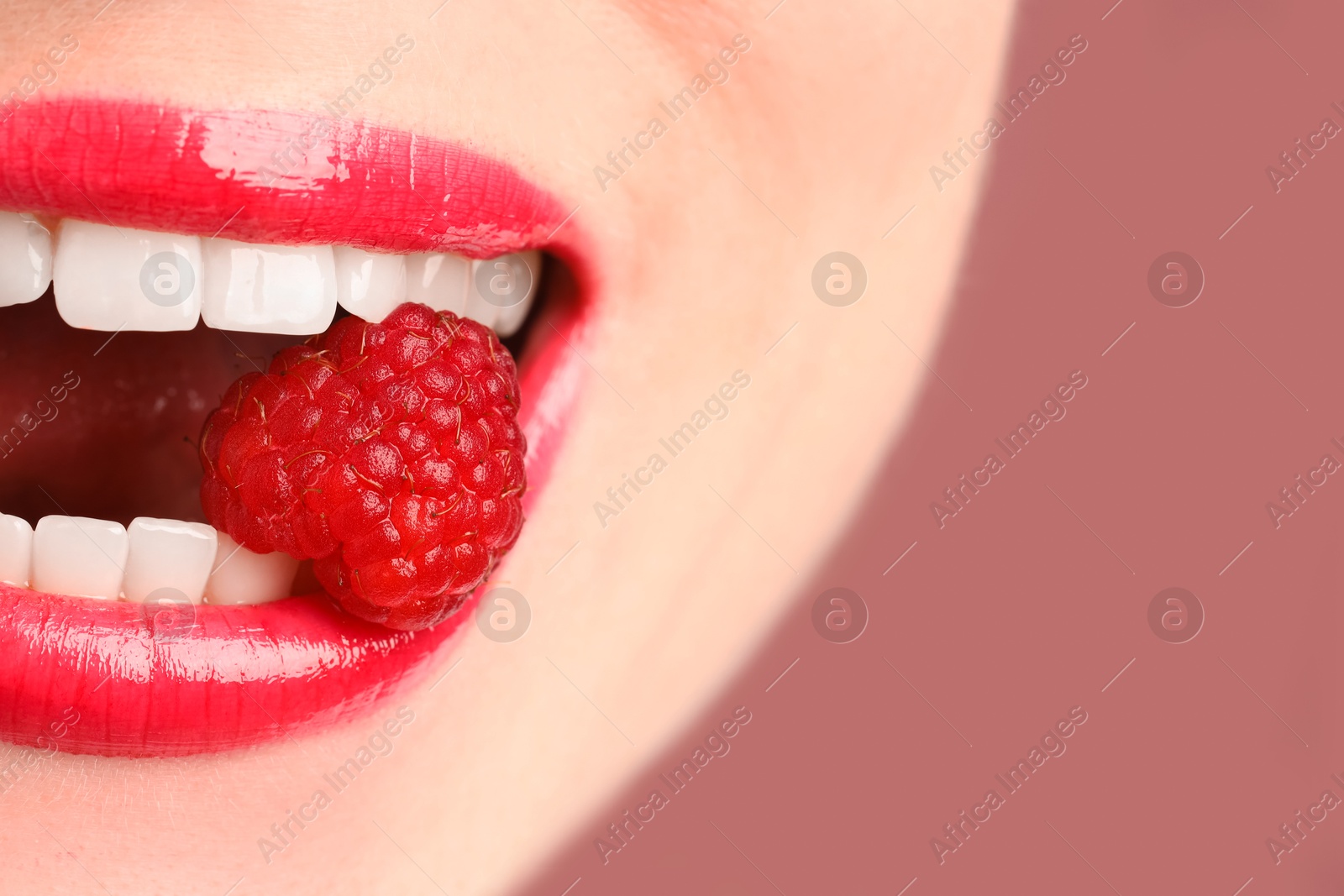 Woman with beautiful lips makeup and raspberry on dusty pink background, closeup. Space for text Photo of Woman with beautiful lips makeup and raspberry on dusty pink background, closeup. Space for text