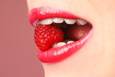 Photo of Woman with beautiful lips makeup and raspberry on dusty pink background, closeup. Space for text