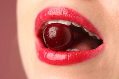 Photo of Woman with beautiful lips makeup and cherry on dusty pink background, closeup