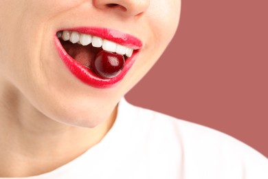 Photo of Woman with beautiful lips makeup and cherry on dusty pink background, closeup