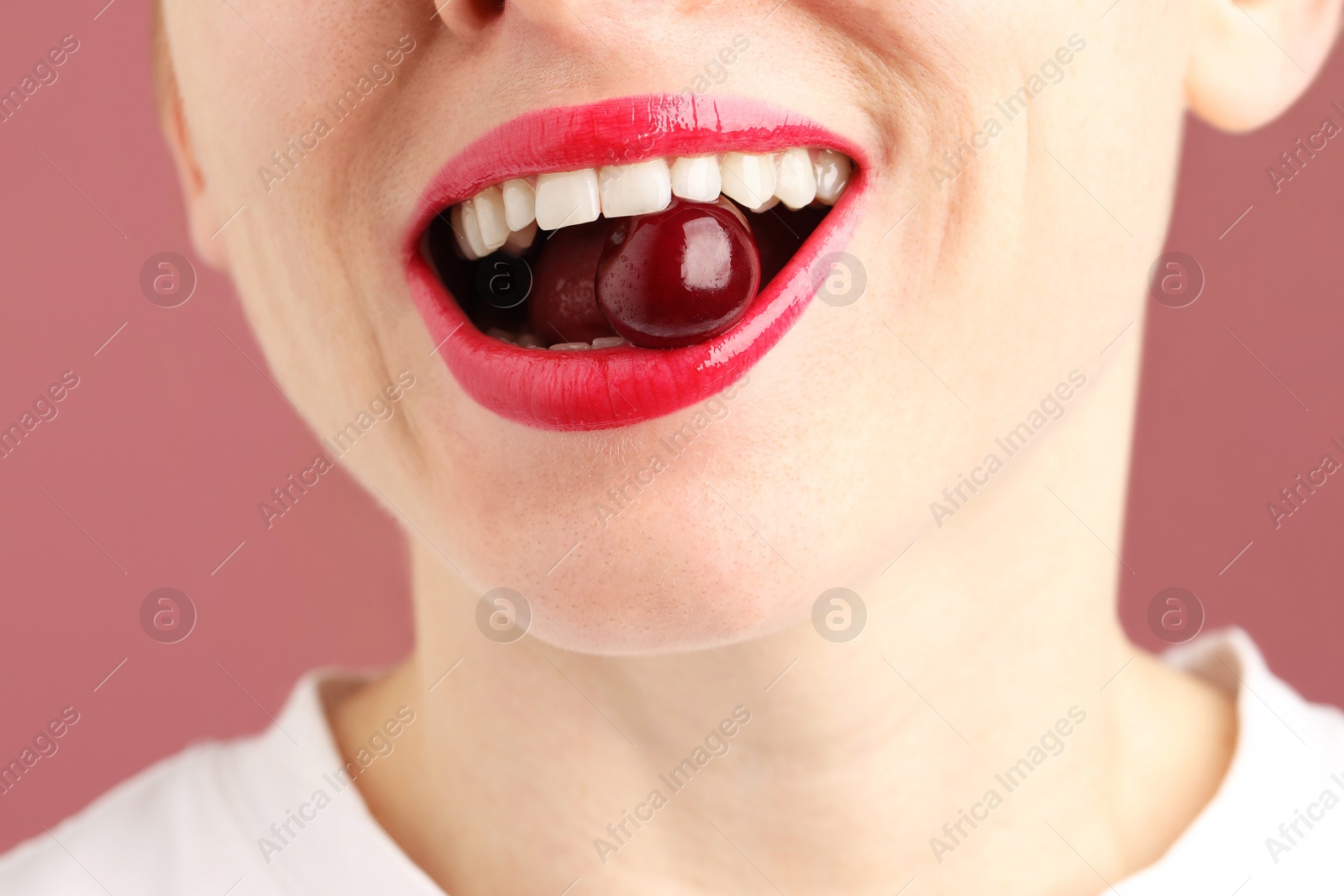 Photo of Woman with beautiful lips makeup and cherry on dusty pink background, closeup