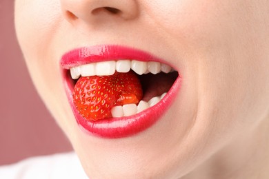 Photo of Woman with beautiful lips makeup and strawberry on dusty pink background, closeup
