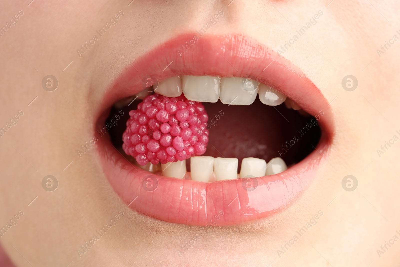 Woman with beautiful lips makeup and raspberry candy, closeup Photo of Woman with beautiful lips makeup and raspberry candy, closeup