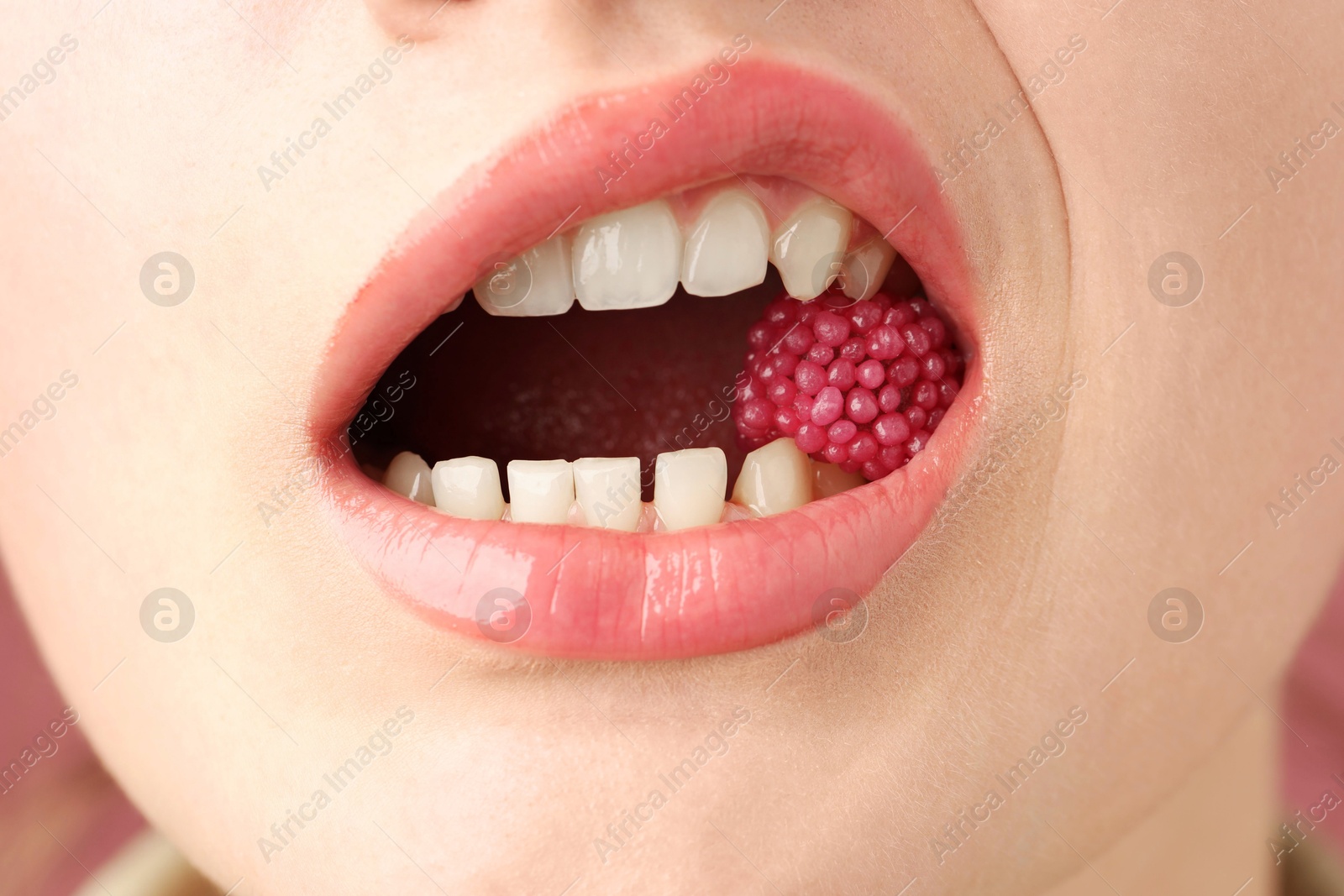 Woman with beautiful lips makeup and raspberry candy, closeup Photo of Woman with beautiful lips makeup and raspberry candy, closeup