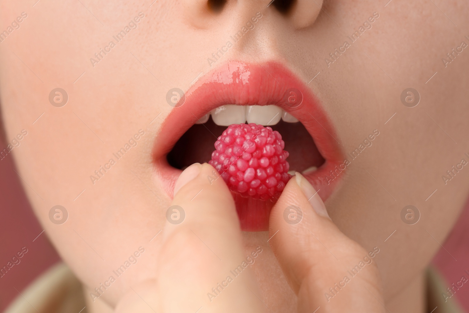 Woman with beautiful lips makeup and raspberry candy, closeup Photo of Woman with beautiful lips makeup and raspberry candy, closeup