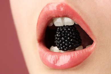 Photo of Woman with beautiful lips makeup and blackberry on dusty pink background, closeup