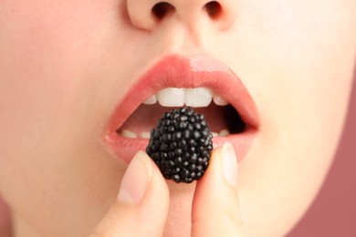 Photo of Woman with beautiful lips makeup and blackberry on dusty pink background, closeup
