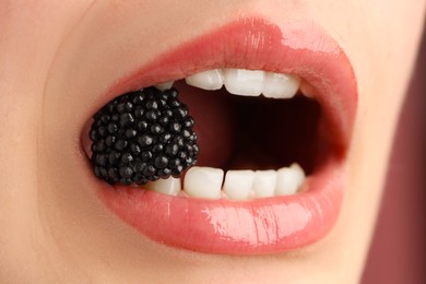 Photo of Woman with beautiful lips makeup and blackberry on dusty pink background, closeup