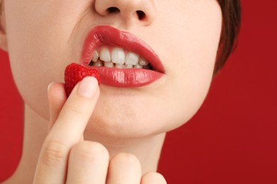 Photo of Woman with beautiful lips makeup and raspberry on red background, closeup