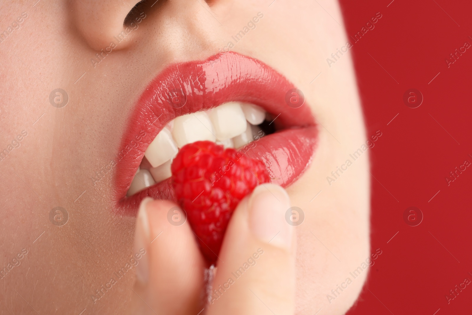 Woman with beautiful lips makeup and raspberry on red background, closeup Photo of Woman with beautiful lips makeup and raspberry on red background, closeup
