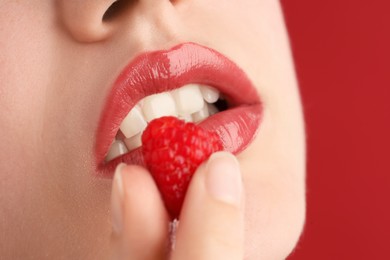 Photo of Woman with beautiful lips makeup and raspberry on red background, closeup