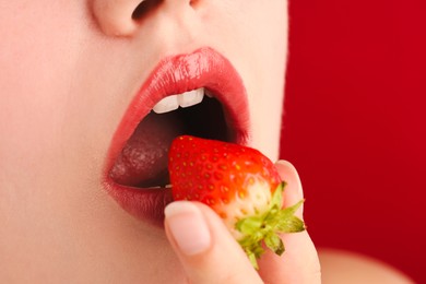 Photo of Woman with beautiful lips makeup and strawberry on red background, closeup. Space for text
