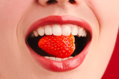 Photo of Woman with beautiful lips makeup and strawberry on red background, closeup
