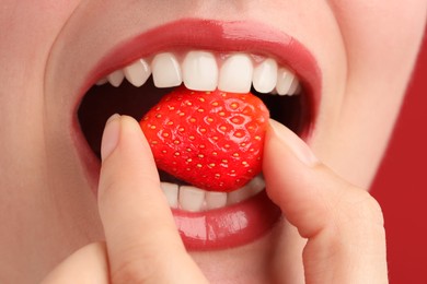 Photo of Woman with beautiful lips makeup and strawberry on red background, closeup