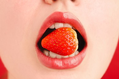 Photo of Woman with beautiful lips makeup and strawberry on red background, closeup