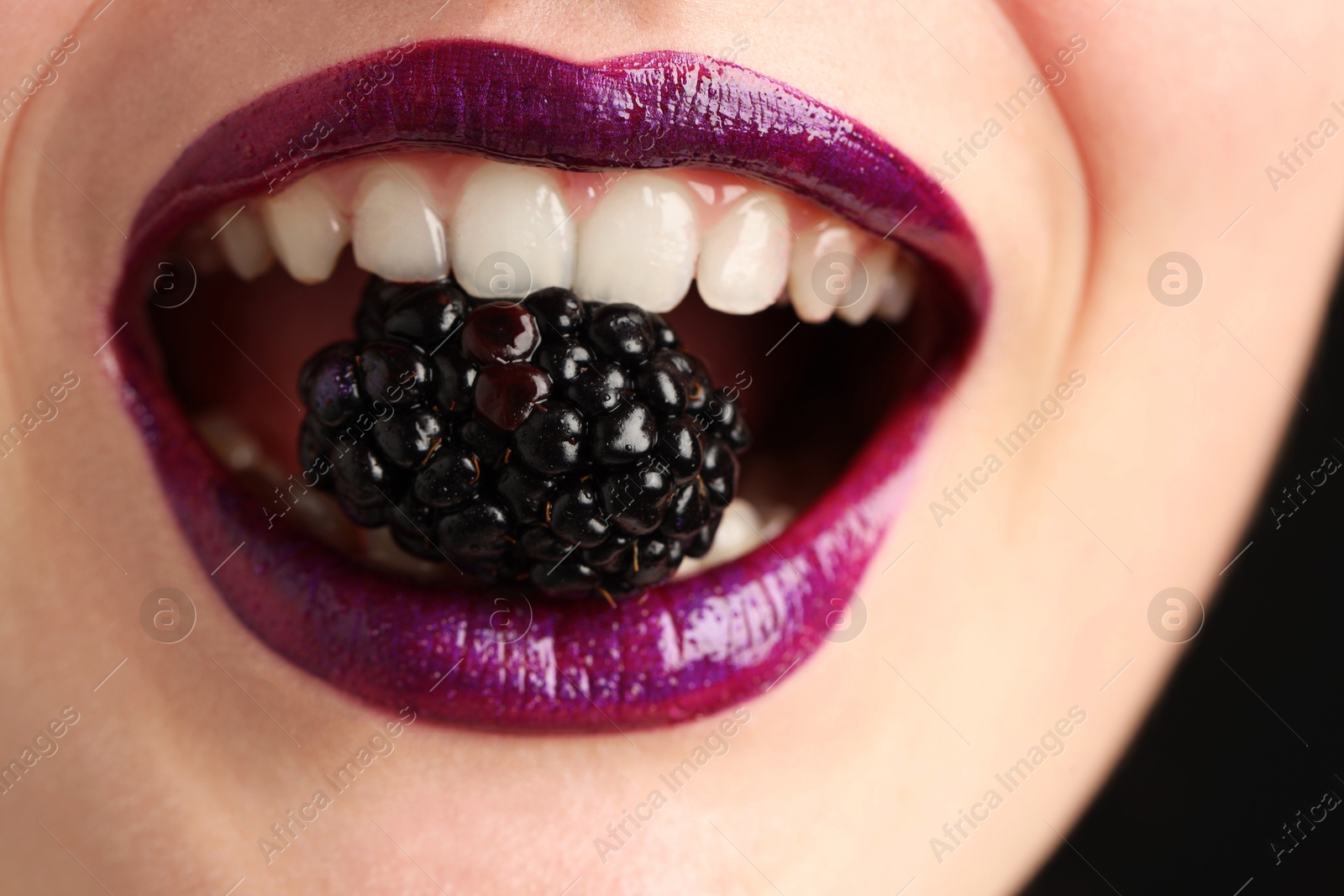 Woman with beautiful lips makeup and blackberry on black background, closeup Photo of Woman with beautiful lips makeup and blackberry on black background, closeup