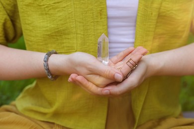 Photo of Woman meditating with crystal to heal or restore her aura outdoors, closeup