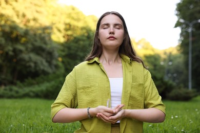Photo of Woman meditating with crystal to heal or restore her aura outdoors