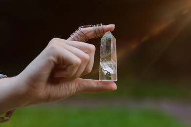 Photo of Woman meditating with crystal to heal or restore her aura outdoors, closeup