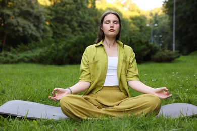 Photo of Woman meditating in lotus pose to heal or restore her aura outdoors
