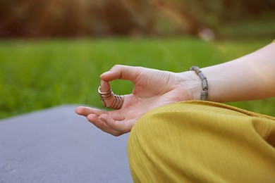 Photo of Woman meditating to heal or restore her aura in park, closeup