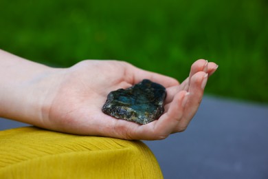 Photo of Woman meditating with crystal to heal or restore her aura outdoors, closeup